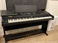 Full view of the Wurlitzer digital keyboard in a black stand with three pedals and music stand attachment.
