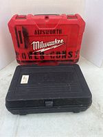 Red Milwaukee tool case and black Ainsworth tool case stacked on floor showing exterior condition