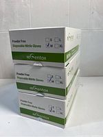 Three stacked boxes of reCentox disposable nitrile gloves labeled powder free, medium size with blue color.