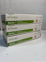 Three stacked boxes of ReGentox disposable nitrile gloves labeled powder free and medium size