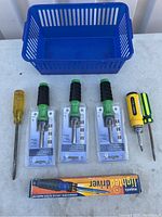 Blue plastic basket with 7 screwdrivers (2 loose, 3 sets packaged) and boxed lighted screwdriver arranged in front