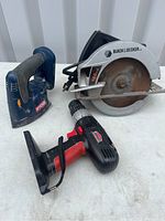 Photo showing Black & Decker circular saw, Ryobi electric sander, and Kobalt drill on white surface.