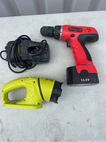 Airco 14.4V cordless drill and yellow flashlight with charger visible, laid on a white surface