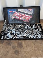 View of full set of over 100 chrome vanadium steel standard and metric sockets in black case with lid showing brand and set details