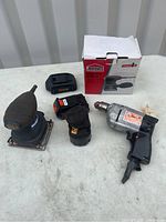 Photo showing two sanders, two batteries, and one corded electric drill. The Jobmate sander box is present and visible.