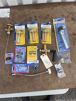 Photo of various plumbing valves, flexible hose, washers, and accessories on a brown surface.