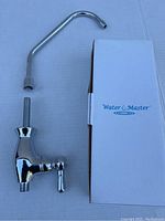 Water Master chrome finish bar/kitchen faucet next to its original box on a light surface.