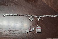 Full view of bracelet laid out with four charms beside it, showing details of each charm and the chain style