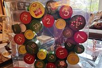 Front view of the Advant Calendar Wreath advent calendar in clear plastic packaging with visible numbered compartments and festive prints.