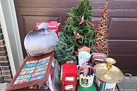 Full lot overview showing Christmas trees, decorative tins, and various containers arranged together including a large fabric pumpkin decoration in the background.
