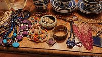 Wide view of assortment of costume jewelry on wood surface showing multiple bracelets and necklaces.