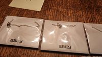 Three Effy necklaces sealed in clear plastic bags on white cards with the Effy logo, displayed on wood surface.