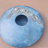 Top view of blue pottery vase showing central opening and textured decorative band with embedded stone fragments.