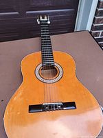 Guitar front view showing the body, sound hole with decorative rosette, and part of the fretboard.