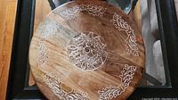 Top-down view of round wooden Lazy Susan showing full carved leaf and floral decoration.