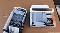 Two open boxes filled with neatly stacked Magic the Gathering cards on a table.