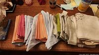 Napkins and linens spread out to show various pastel and neutral tones folded on a wooden surface.