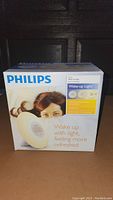 Front view of the Philips Wake Up Light box showing product image and key features.