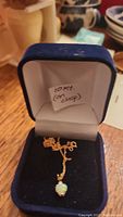 Necklace displayed in navy velvet jewelry box showing chain and opal pendant with handwritten note indicating ’10kt (on clasp)’