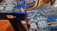 Two unopened boxes of Emerald outdoor 100 icicle lights with clear bulbs and white cords shown on a table.