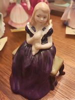 Front angle showing the girl in purple dress holding the rabbit while seated on a small bench.