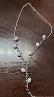 Silver chain necklace laid flat, showing light pink and white freshwater pearls spaced on the chain in a Y-shape design.