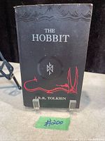 Front cover of the vintage 1999 paperback edition of The Hobbit showing black cover with red dragon illustration and white text.