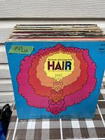 Stack of vinyl records with visible album cover for The Music and Songs from HAIR