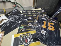 Lot of Hamilton Tiger-Cats collectibles including flag, jersey, bags, and cloth laid out on table