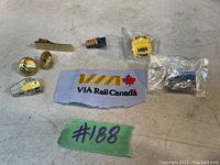 Photo showing seven VIA Rail Canada pins and a fabric patch, two pins remain sealed in plastic bags.