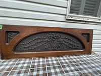 Front view showing entire rectangular oak panel with central arched inset containing carved floral and vine design, and corner triangular floral carvings.
