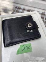 Closed black leather Audi wallet showing embossed logo and metal Audi rings emblem on clasp