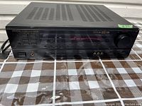 Full front view of Denon surround receiver showing buttons, volume knob, headphone jack, and LED display.