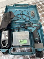 Top view of the open plastic carrying case showing the cordless drill, charger, holster, and box of bits inside.