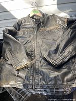 Full view of dark brown leather jacket showing front zipper, zippered chest pocket, and zippered cuffs on sleeves.