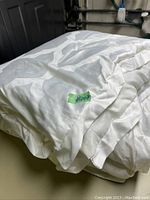 Image showing the folded white queen size comforter with a subtle floral pattern and a green tag labeled '#2008'.