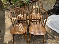 Four matching wooden hoop back Windsor chairs arranged outdoors