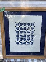 Framed print showing a grid of blue house illustrations, with a wide blue matte and gilded wood frame.