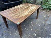 Full view of the solid wood rectangular table showing the tabletop surface and four legs.