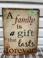 Front view of the rectangular vintage metal wall art featuring the quote 'A family is a gift that lasts forever'. Shows slight weathering and age wear.