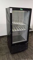 Front view of upright black glass‐door refrigerator showing cabinet, door gasket and condenser vent