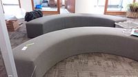 Front view of two curved gray benches positioned end to end