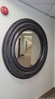 Front view of large round wall mirror with dark carved frame and visible wear