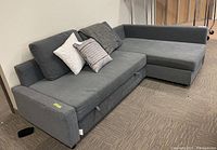 Front left view of gray sectional showing pullout trundle handle