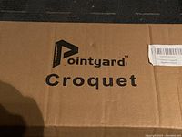 Cardboard box with Pointyard logo and 'Croquet' printed on it.
