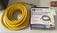 Photo of thick yellow air hose coiled next to boxed Natural Gas Conversion Kit