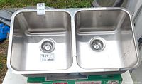 Double basin stainless steel undermount sink with strainers and drain baskets, measuring 31x17x8 inches.