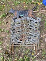 Stack of 12 cast iron garden edging pieces with decorative leaf and scroll design, showing rust, with a rusty metal cat silhouette behind them on the ground.