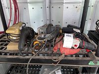 Overview of multiple power tools including drills, sanders and jigsaw on a metal rack shelf.