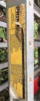 Close-up photo of safety and usage warning label on metal car ramp, indicating 700 lb (318 kg) capacity and manufacturer information (Proma, Sumex Tools Corp.)